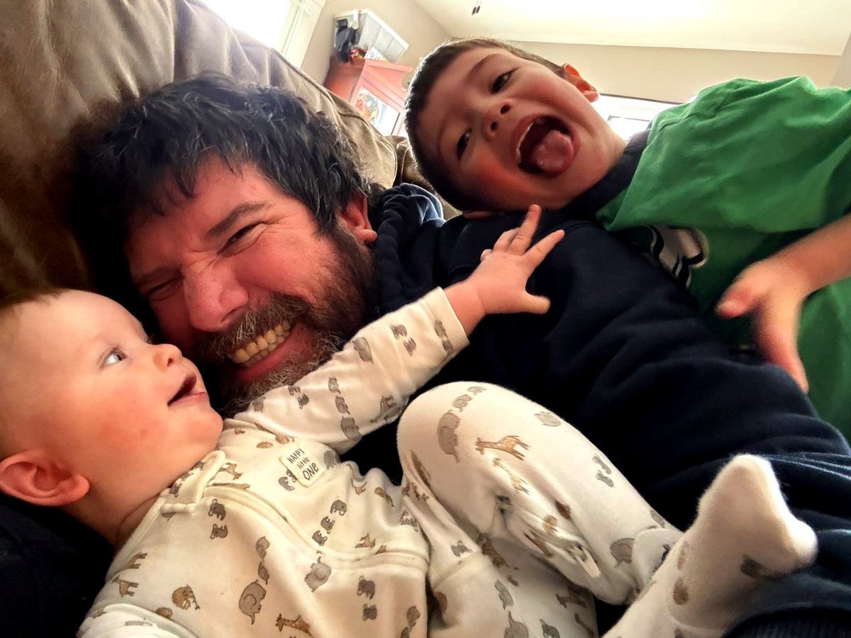 Tom laughing on the couch with two of his kids