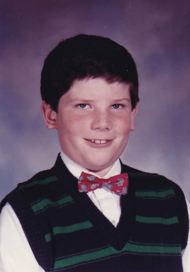 School portrait of Tom as a boy in a bow tie and sweater vest